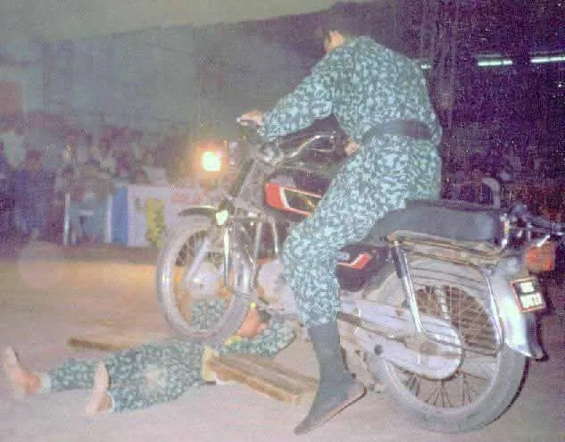 Motorcycle rolling over a student lying on boards at a night demonstration