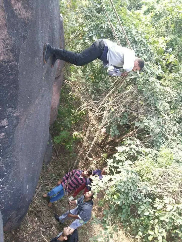 Student rappelling down a rock face while others watch