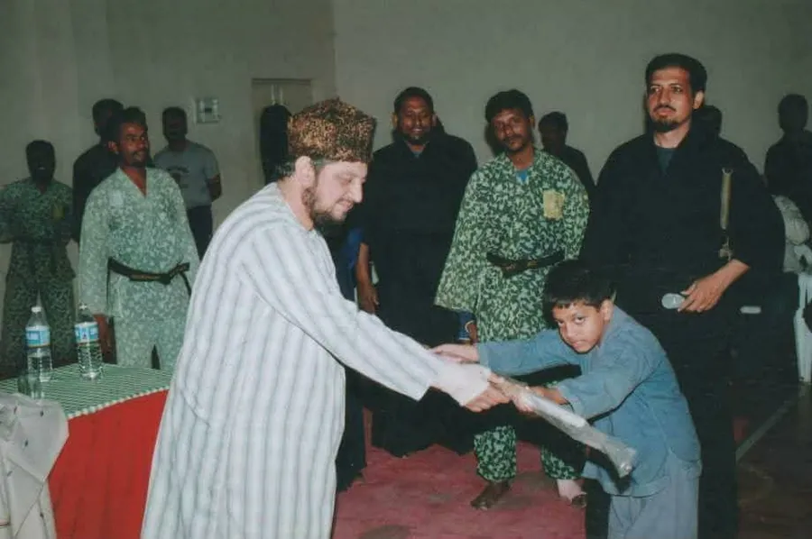 A young student receiving a training weapon at a ceremony