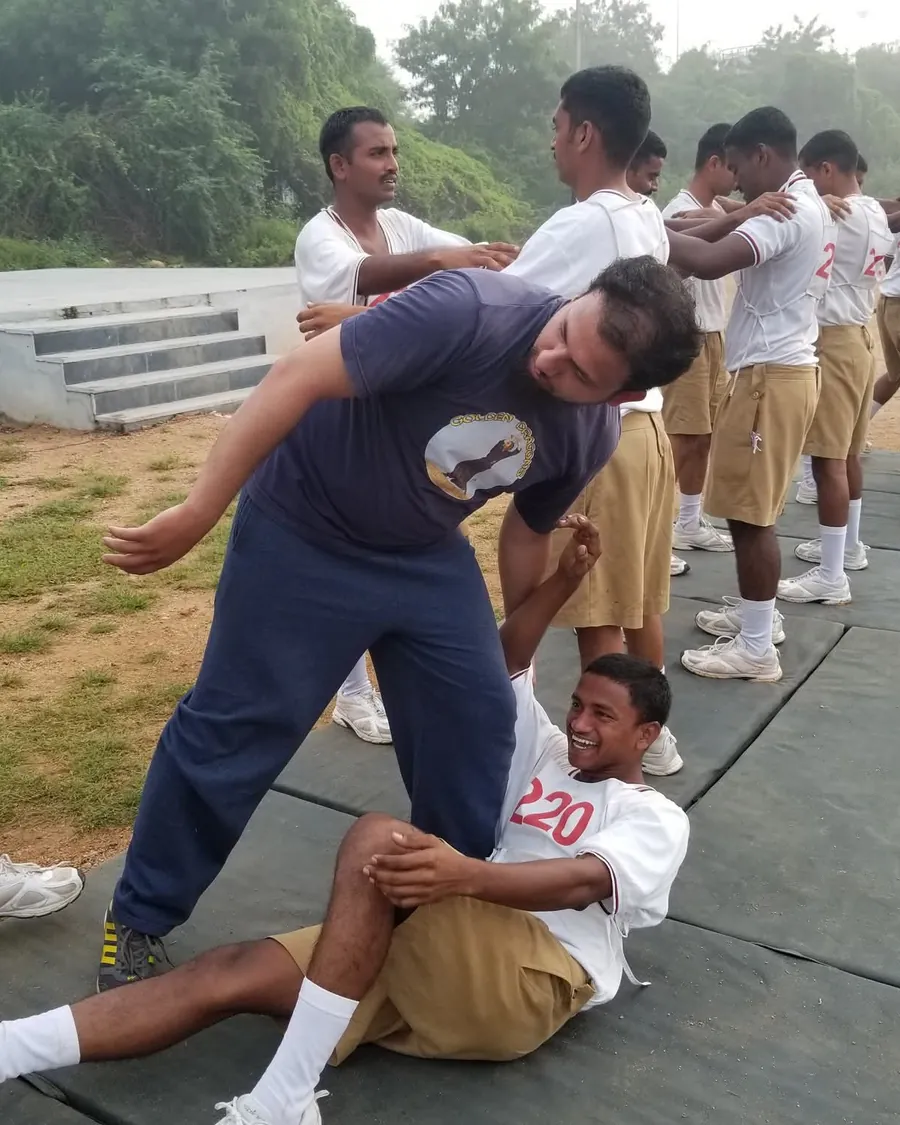 Golden Dragons instructor teaching a takedown to smiling uniformed recruits on training mats
