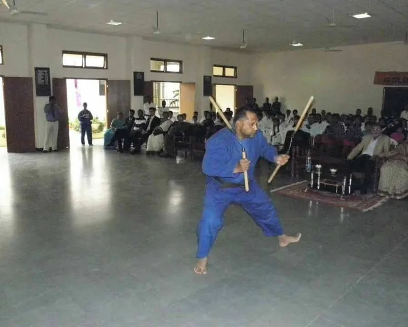 Senior student in blue gi performing a nunchaku form before an audience